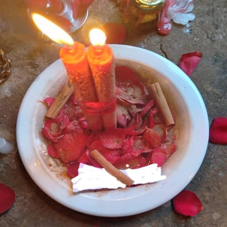 Tazón con velas encendidas, pétalos de rosa y canela. Ambiente decorativo y espiritual.